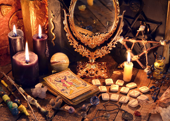 witchcraft items, candles, and gold framed mirror alongside tarot cards